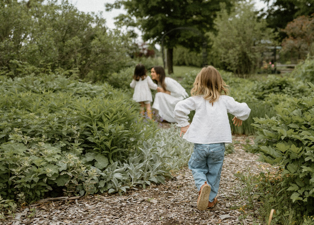 Child running down a garden path toward her mother during an outdoor session photographed by a Vermont family photographer.