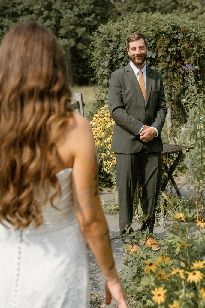 Bride walking toward groom during an emotional first look in a Vermont garden wedding setting.