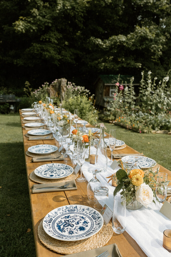 Outdoor reception table set with vintage blue china and wildflower arrangements at one of Vermont’s intimate wedding locations.