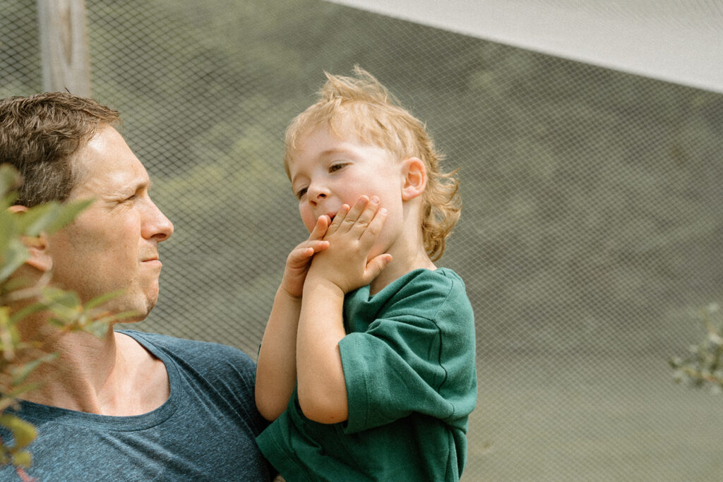 Toddler shoving a blueberry in his mouth while dad holds him.