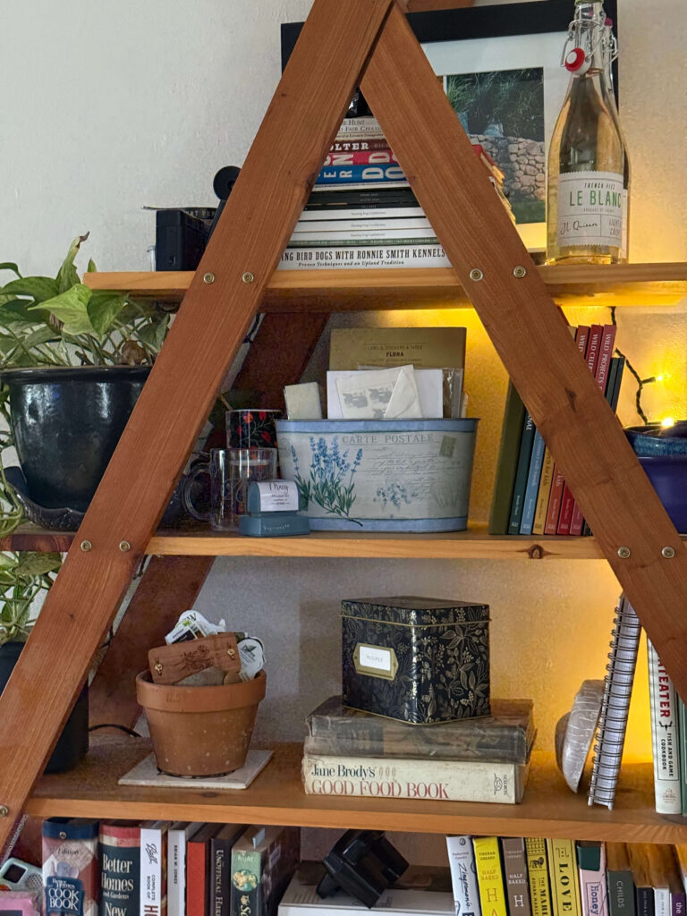 photo of a-frame bookshelf with recipe box  and books