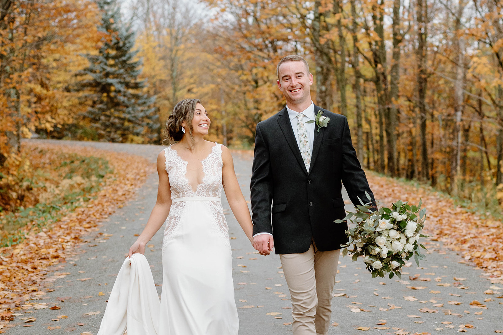 bride and groom walking down road surrounded by vermont foliage