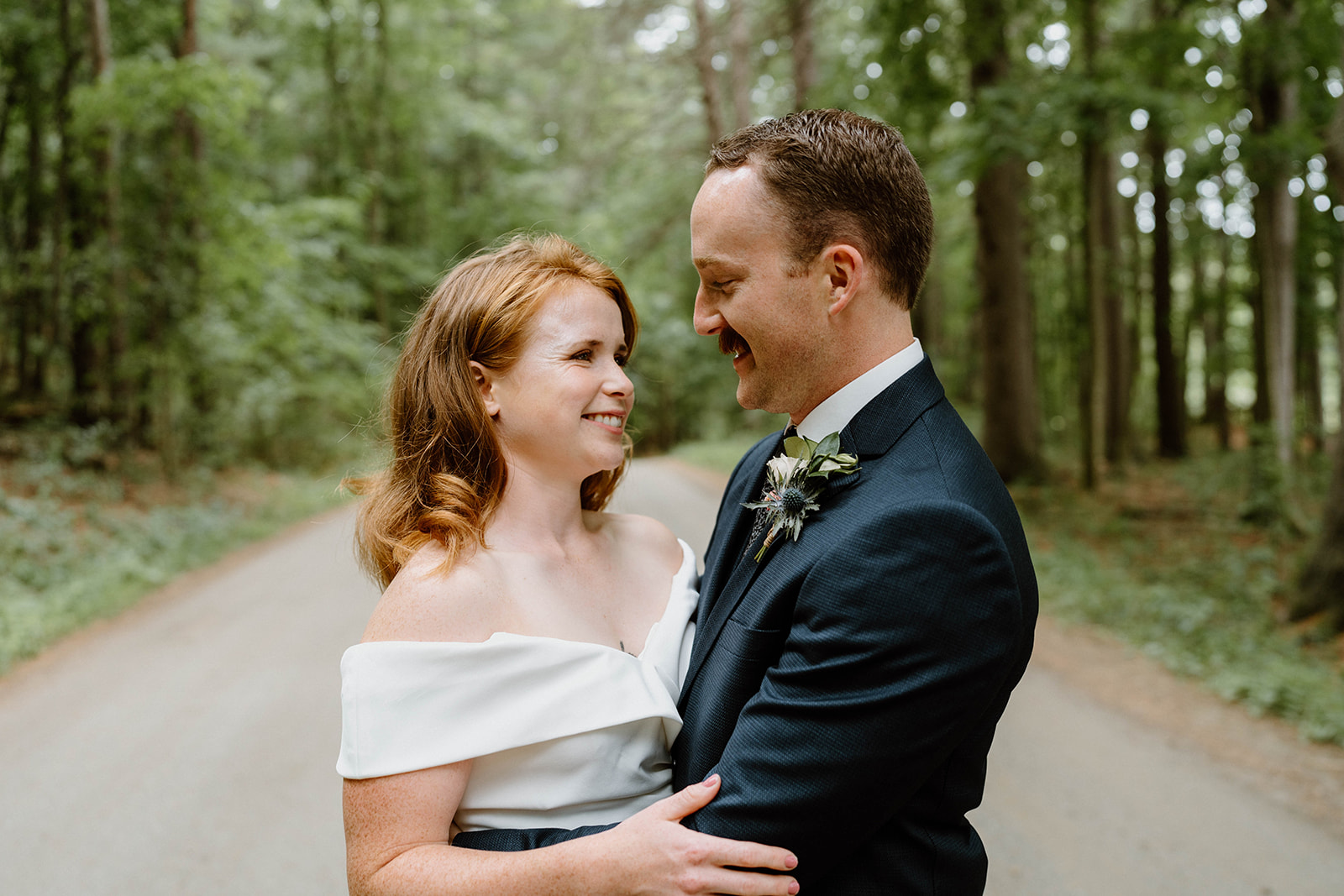 bride and groom smiling on tree-lined path at Shelburne Farms in Vermont