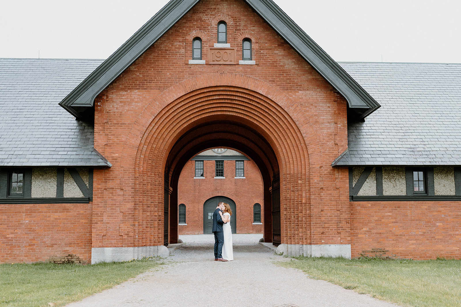 bride and groom standing under brick arch at the country estate at Shelburne Farms