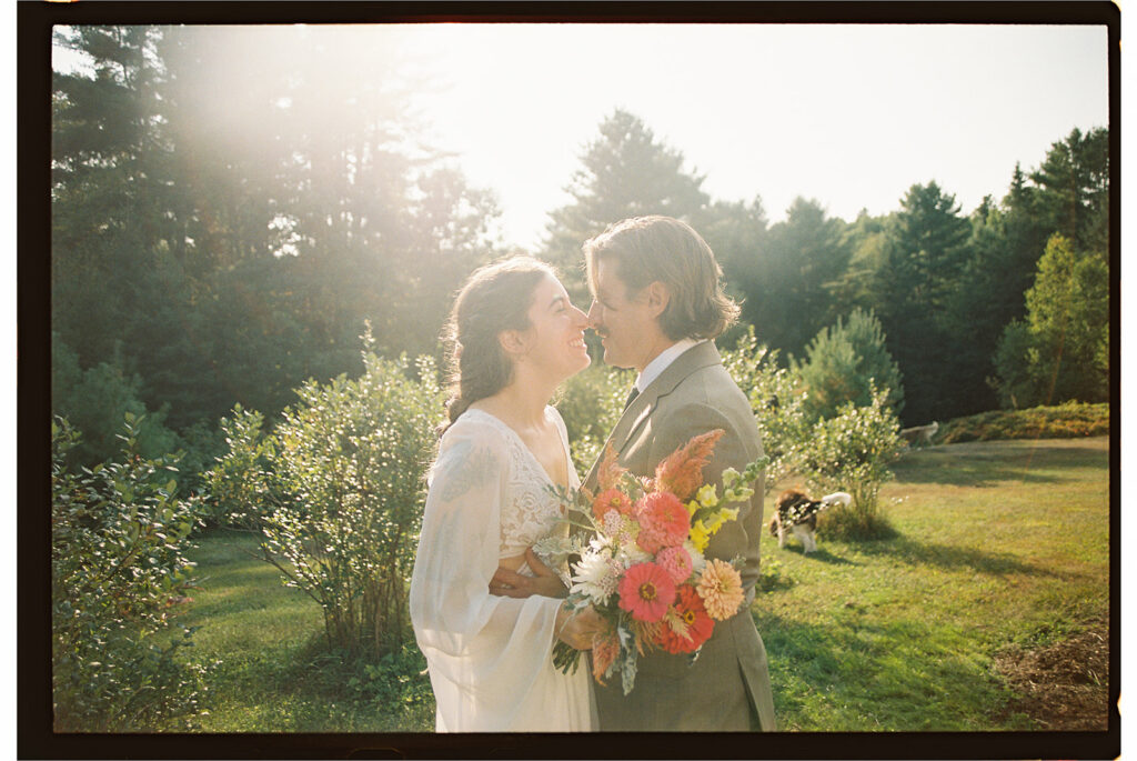 Bride and groom smiling in warm golden light during a Vermont elopement, captured by a documentary-style elopement photographer in a quiet garden setting.