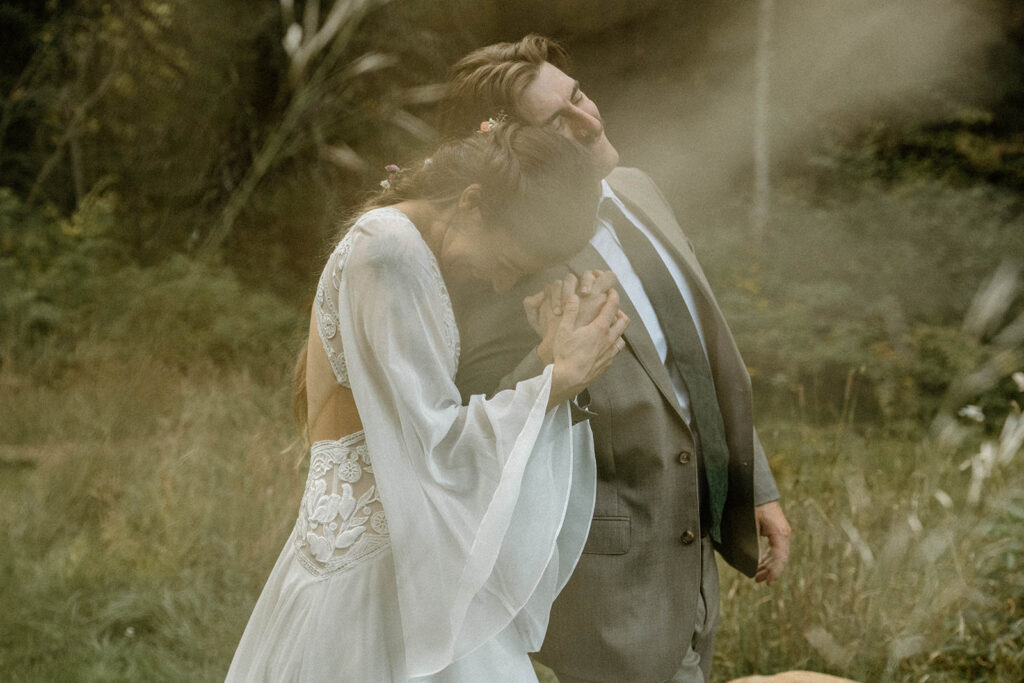 Bride leaning her head on the groom’s shoulder in a misty forest portrait after their intimate Vermont wedding ceremony.