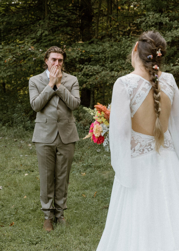 Groom reacting emotionally during a first look in the forest before a Vermont intimate wedding ceremony photographed by an intimate wedding photographer.