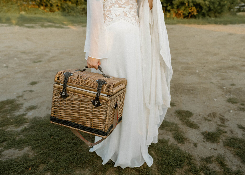 Bride holding a woven picnic basket after her Vermont elopement ceremony at a scenic countryside intimate wedding location.