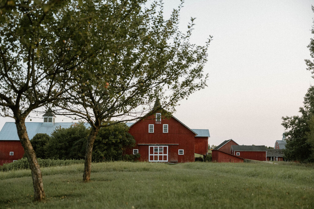 Red barn and orchard trees at a rustic Vermont wedding venue known for scenic intimate wedding locations.