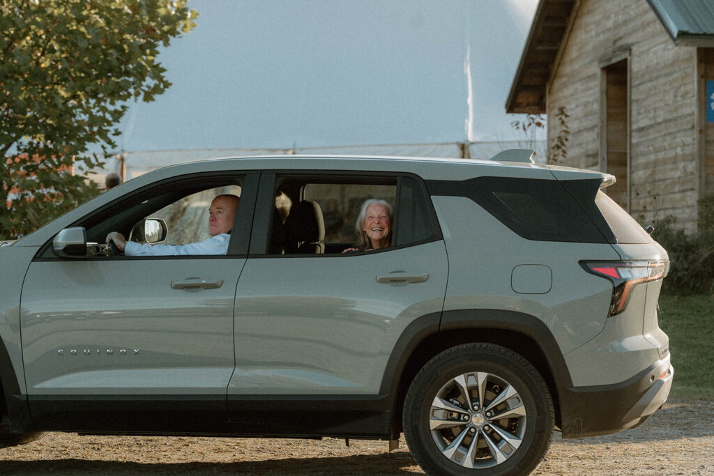 Wedding guest smiling out car window while arriving at backyard wedding reception in Greensboro, Vermont.